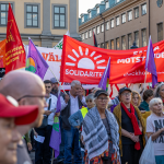 Bild på demonstration inklusive Solidaritets banderoll i rött och vit logga.